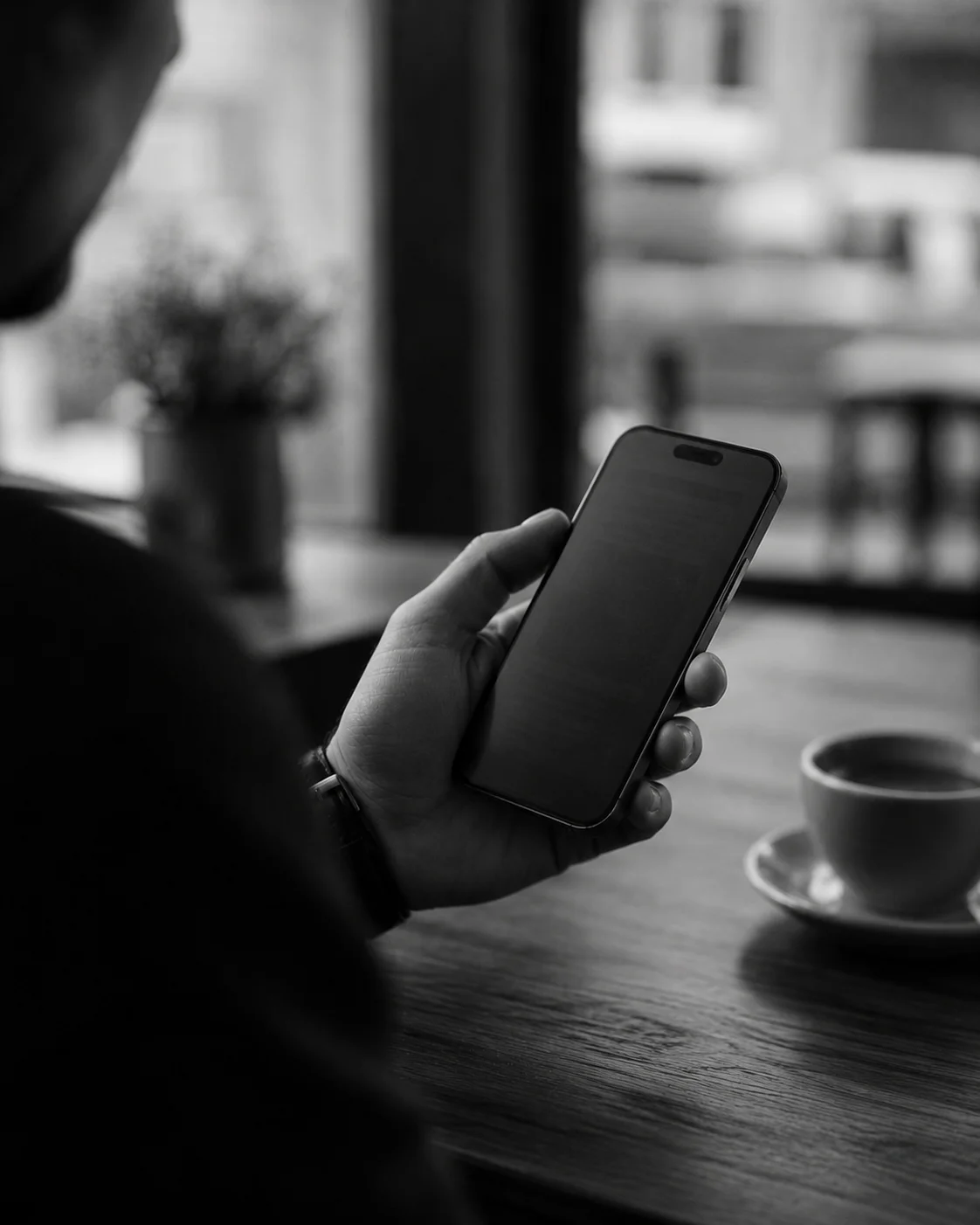 A hand holding a phone at a café table